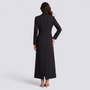Mujer con blazer largo negro entallado con hebilla, vista trasera