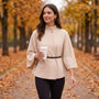 Mujer paseando en otoño con una capa corta de cuello alto y cinturón