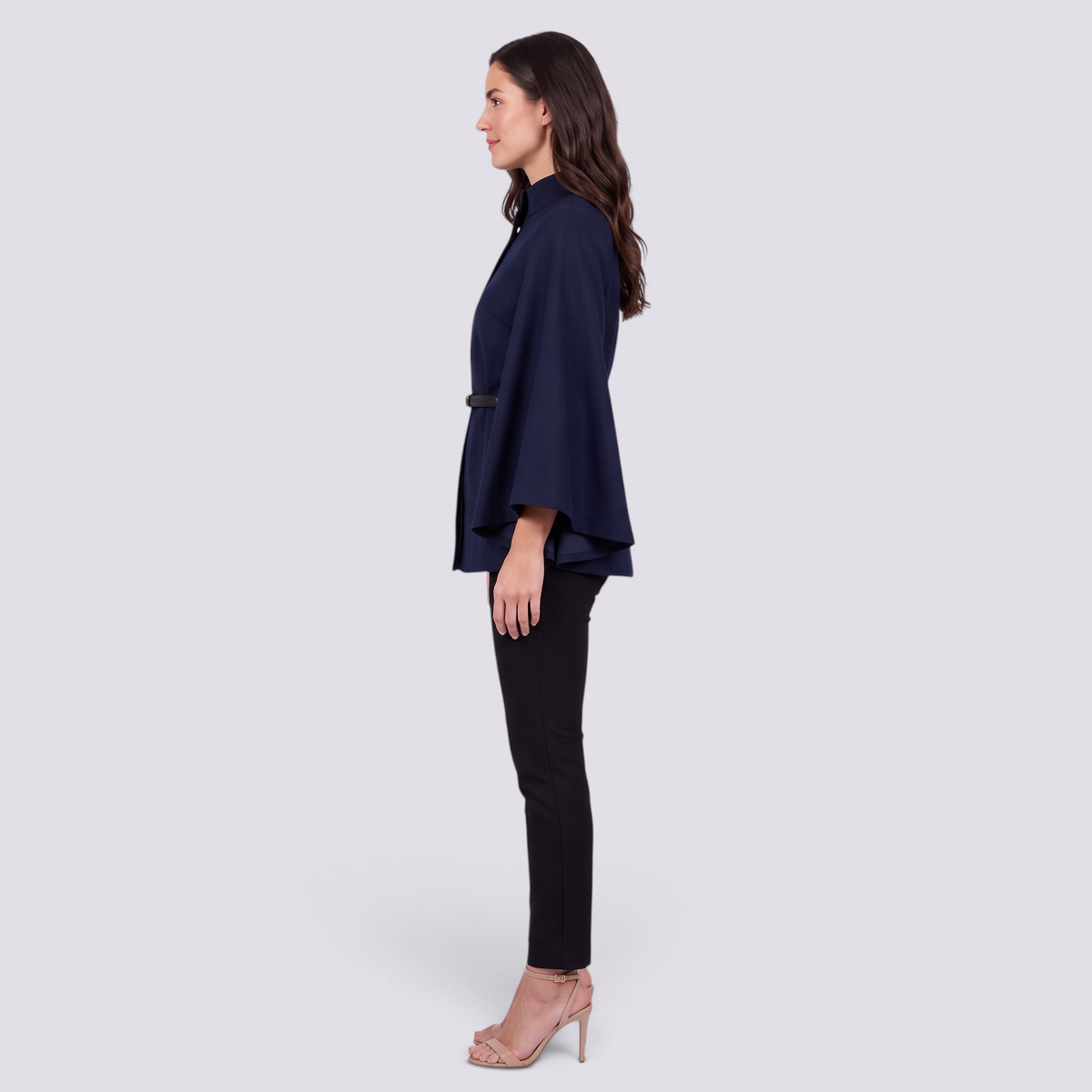 Mujer con capa de manga murciélago y cinturón fino en azul marino, vista lateral