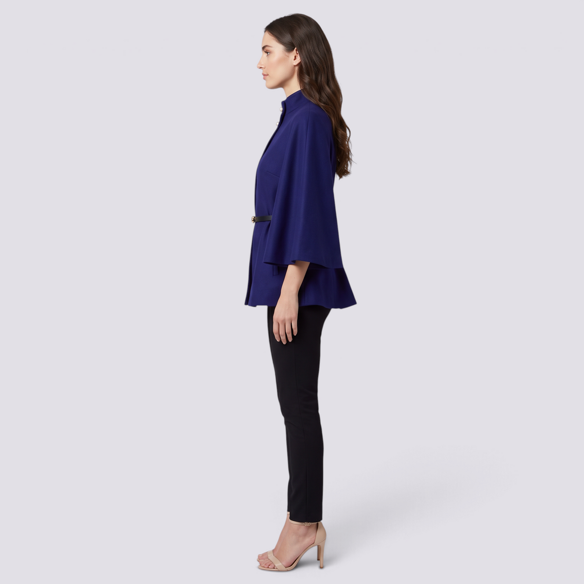 Mujer con capa de manga murciélago y cinturón fino en azul rey, vista lateral
