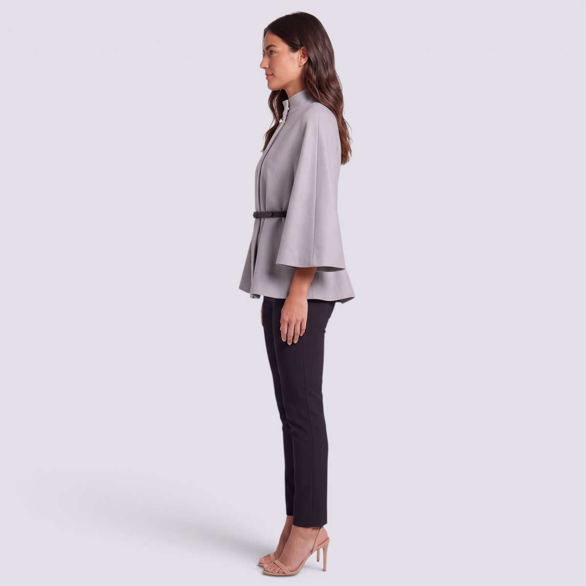 Mujer con capa de manga murciélago y cinturón fino en gris claro, vista lateral