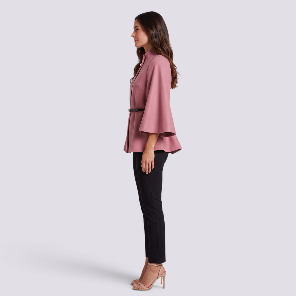 Mujer con capa de manga murciélago y cinturón fino en rosa, vista lateral