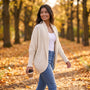 Mujer paseando en otoño con un cárdigan abierto de punto con manga murciélago y cuello chal en color crema