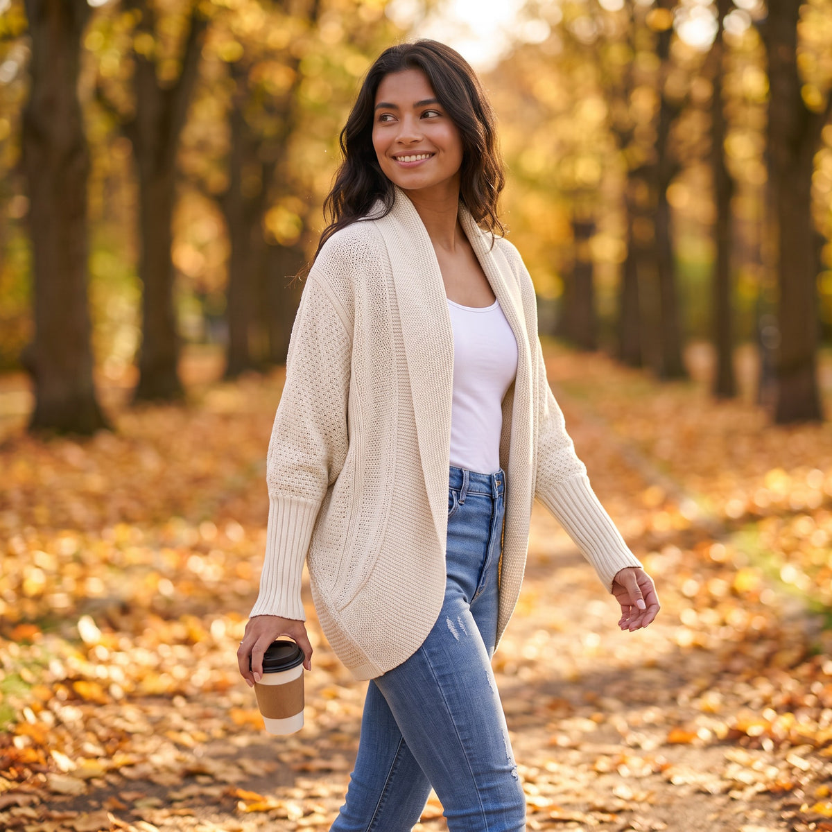 Mujer paseando en otoño con un cárdigan abierto de punto con manga murciélago y cuello chal en color crema