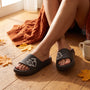 Chanclas de plataforma negras con gato en relieve sobre suelo de madera con hojas de otoño y manta de punto