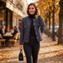 Mujer paseando por una calle en otoño con una chaqueta de tweed de botones dorados