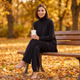 Conjunto jersey largo y pantalón ancho mujer en negro, look de otoño sentada en un banco del parque