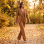 Mujer paseando en otoño con un traje de tres piezas camel con blazer, chaleco y pantalón ancho