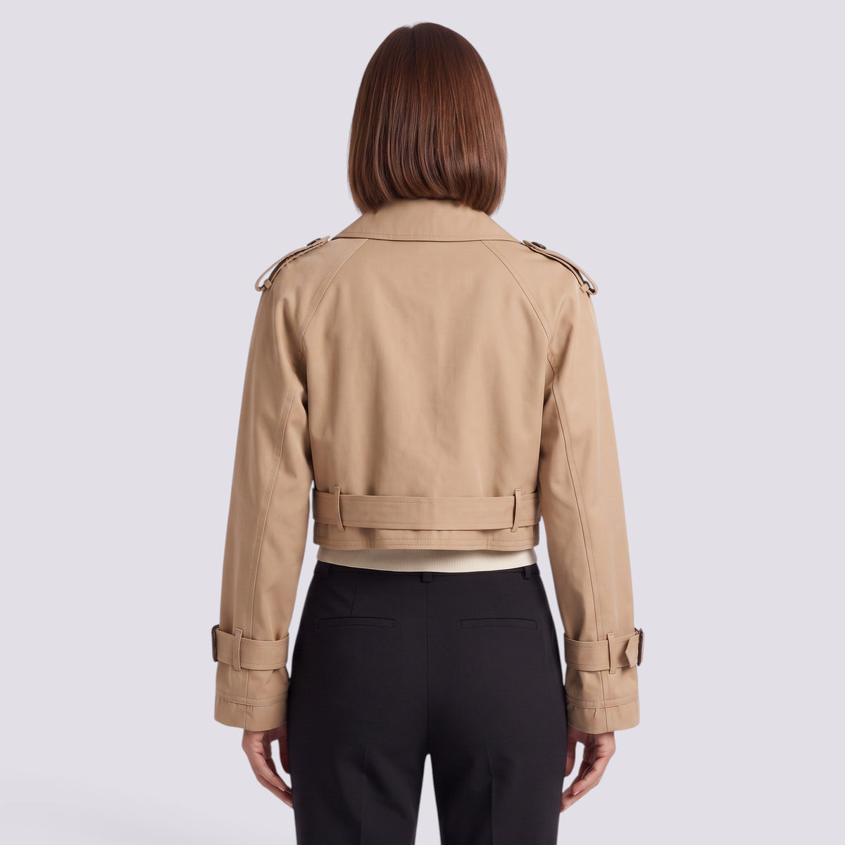 Back view of an Essyro beige cropped windbreaker jacket with epaulettes and belted cuffs worn over black trousers