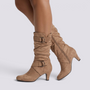 Essyro slouch boots in beige faux suede with mid-curved heels, round toes, and decorative side buckle straps.