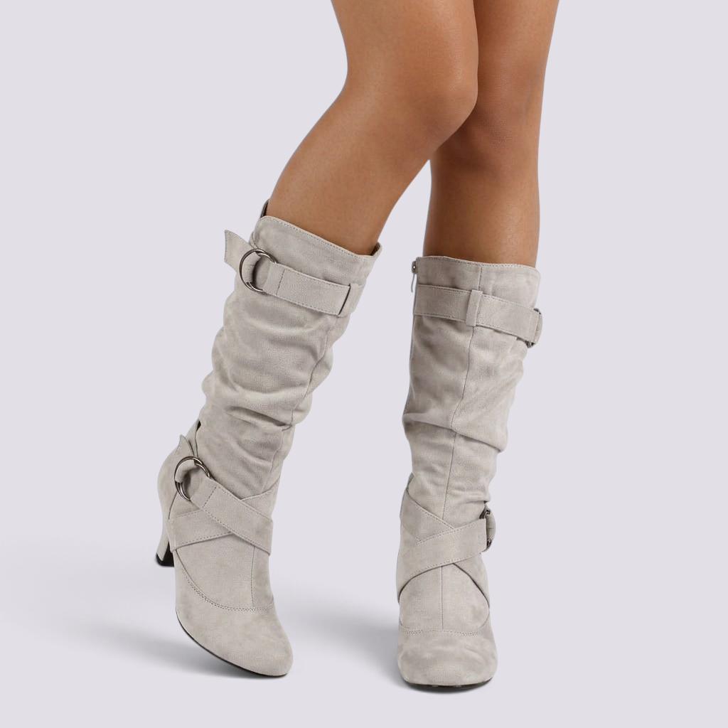 Essyro slouch boots in beige faux suede with mid-curved heels, decorative buckle straps, and a soft pleated shaft.