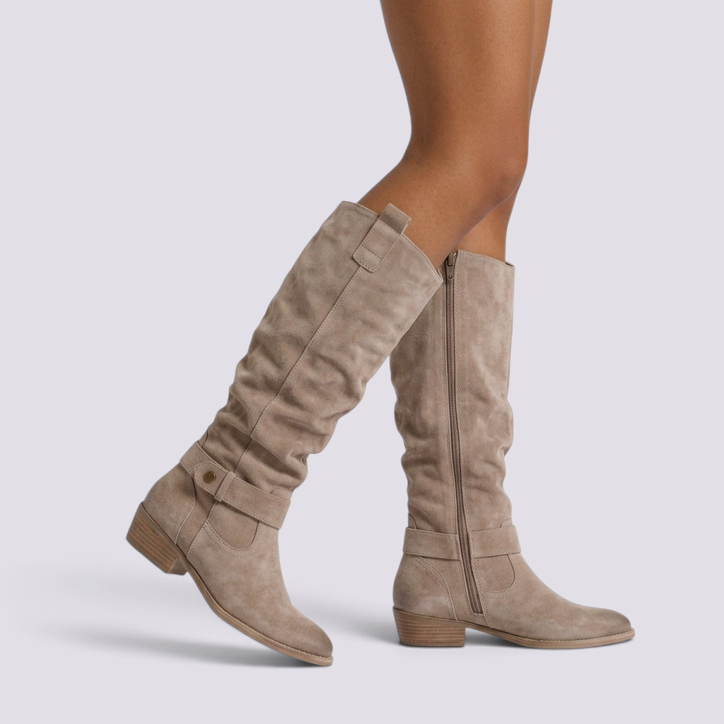 Essyro knee-high slouch boots in beige suede with a low block heel, round toe, and decorative ankle strap detail.