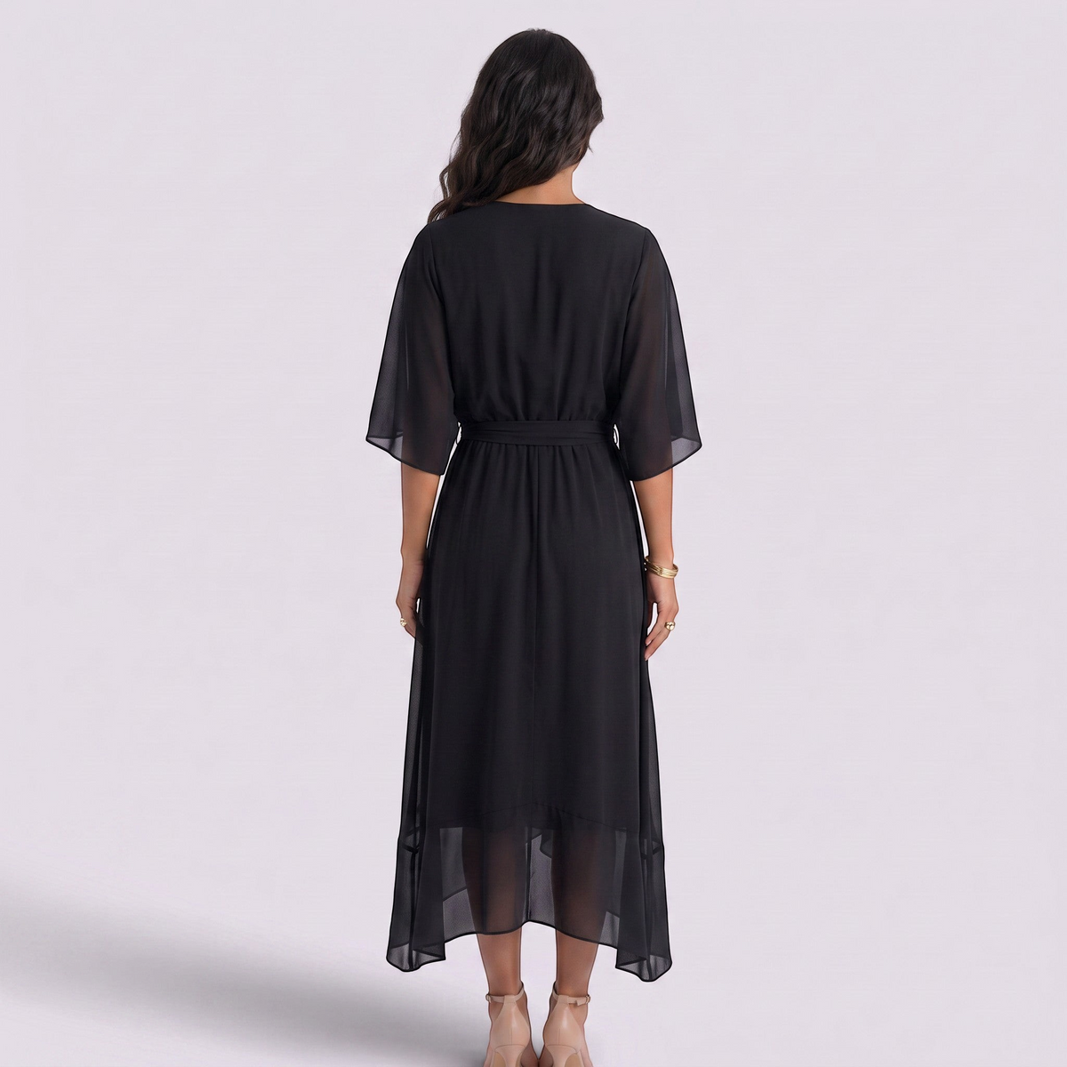 Back view of a woman wearing an Essyro black midi dress with batwing sleeves, cinched waist, and asymmetric hem.
