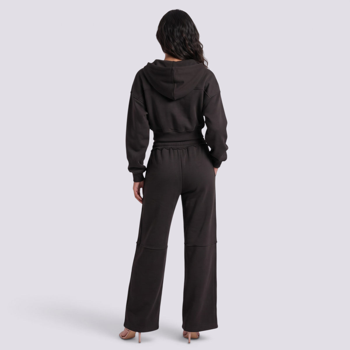 Back view of a woman wearing an Essyro black cropped hoodie and matching wide-leg trousers with visible seam details.
