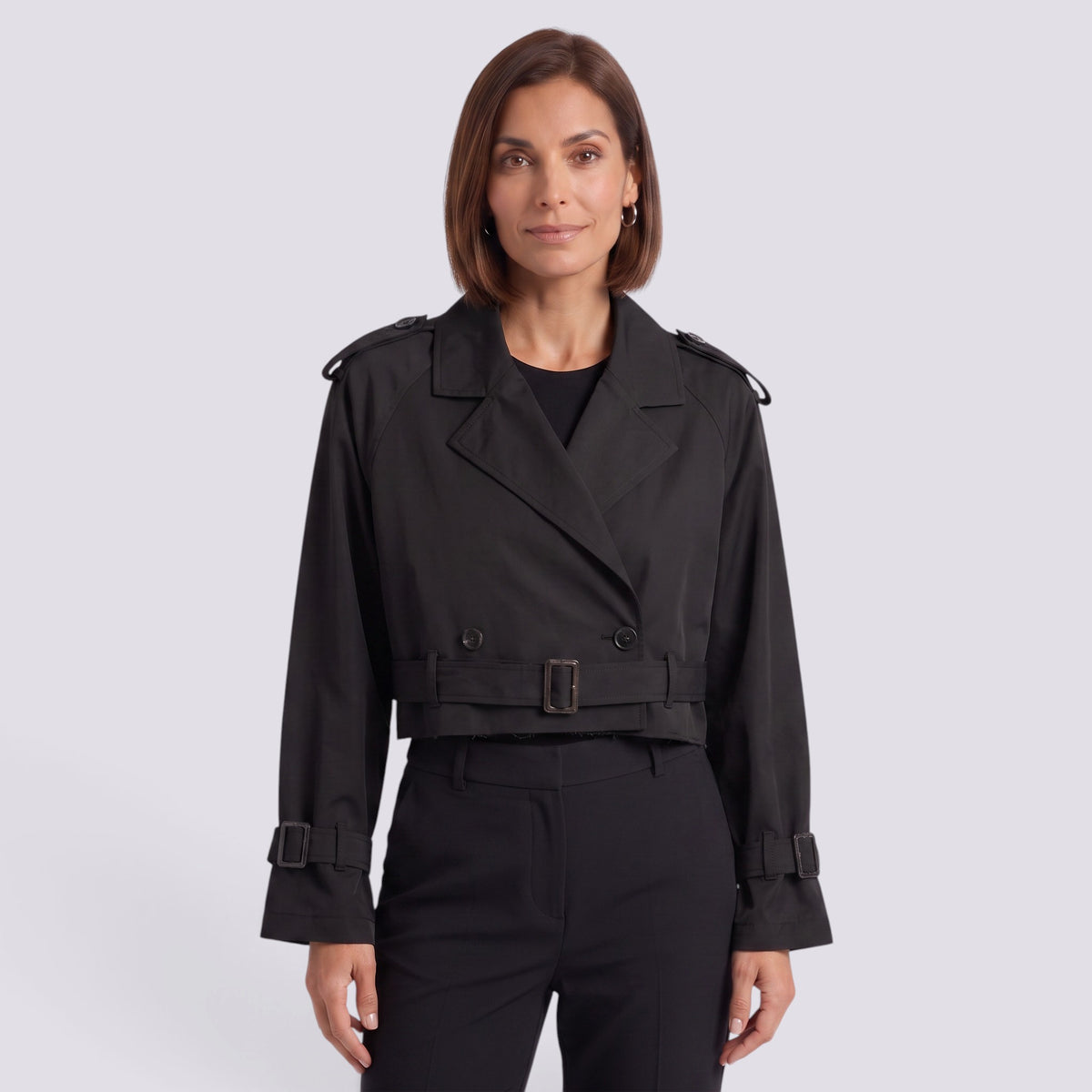 Essyro black cropped windbreaker jacket with trench-style lapels, belted waist, and buckle cuffs on a female model.