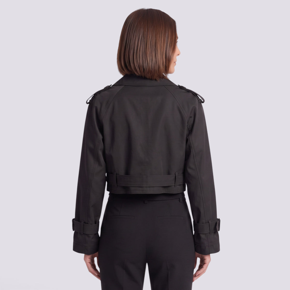 Back view of a woman wearing an Essyro black cropped windbreaker jacket with epaulettes and belted cuffs