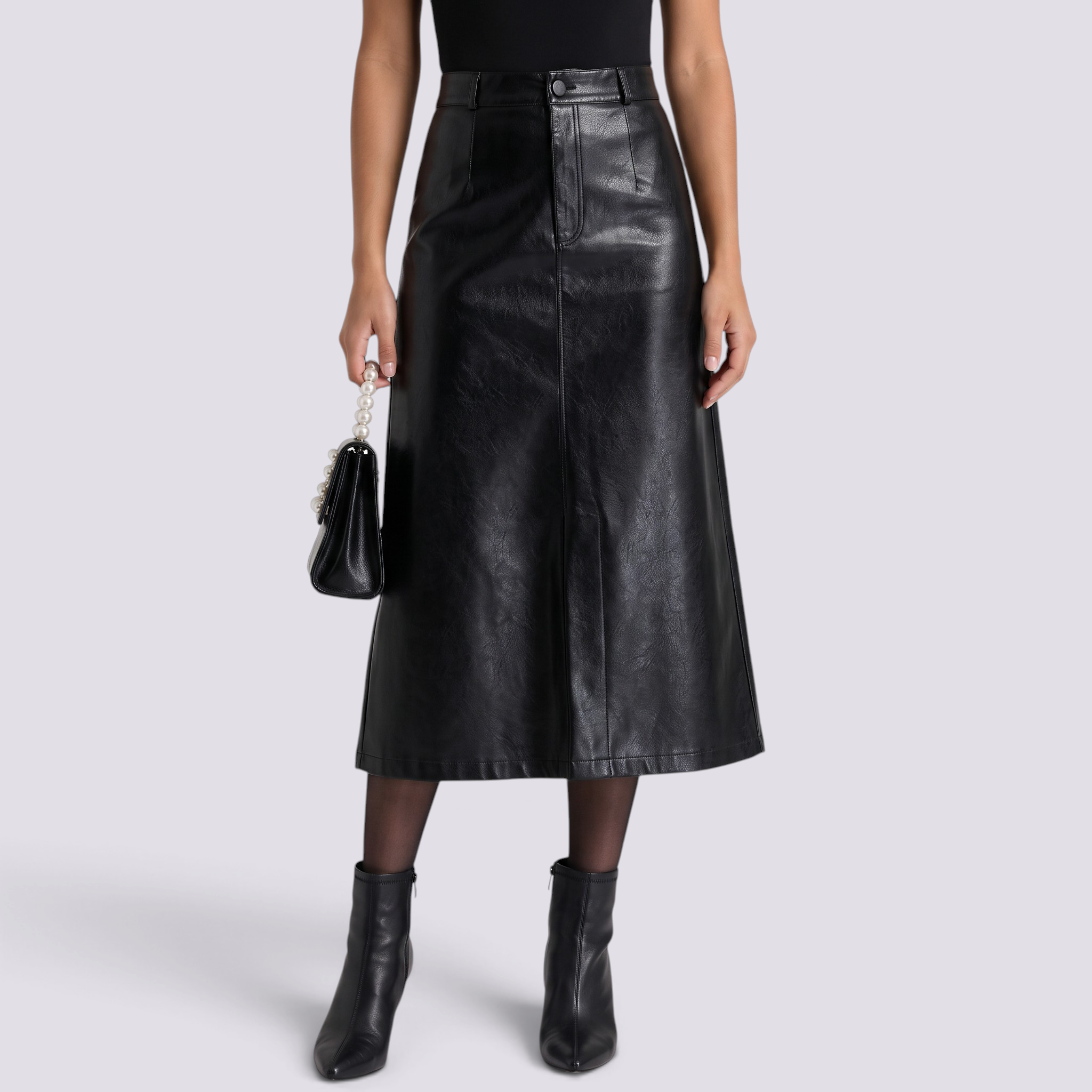 Essyro black faux leather midi skirt with high waist, front slit, and A-line silhouette worn with black ankle boots.