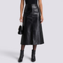Essyro black faux leather midi skirt with high waist, front slit, and A-line silhouette worn with black ankle boots.