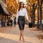 Essyro high-waisted black faux leather pencil skirt worn by a woman walking on a city sidewalk in autumn