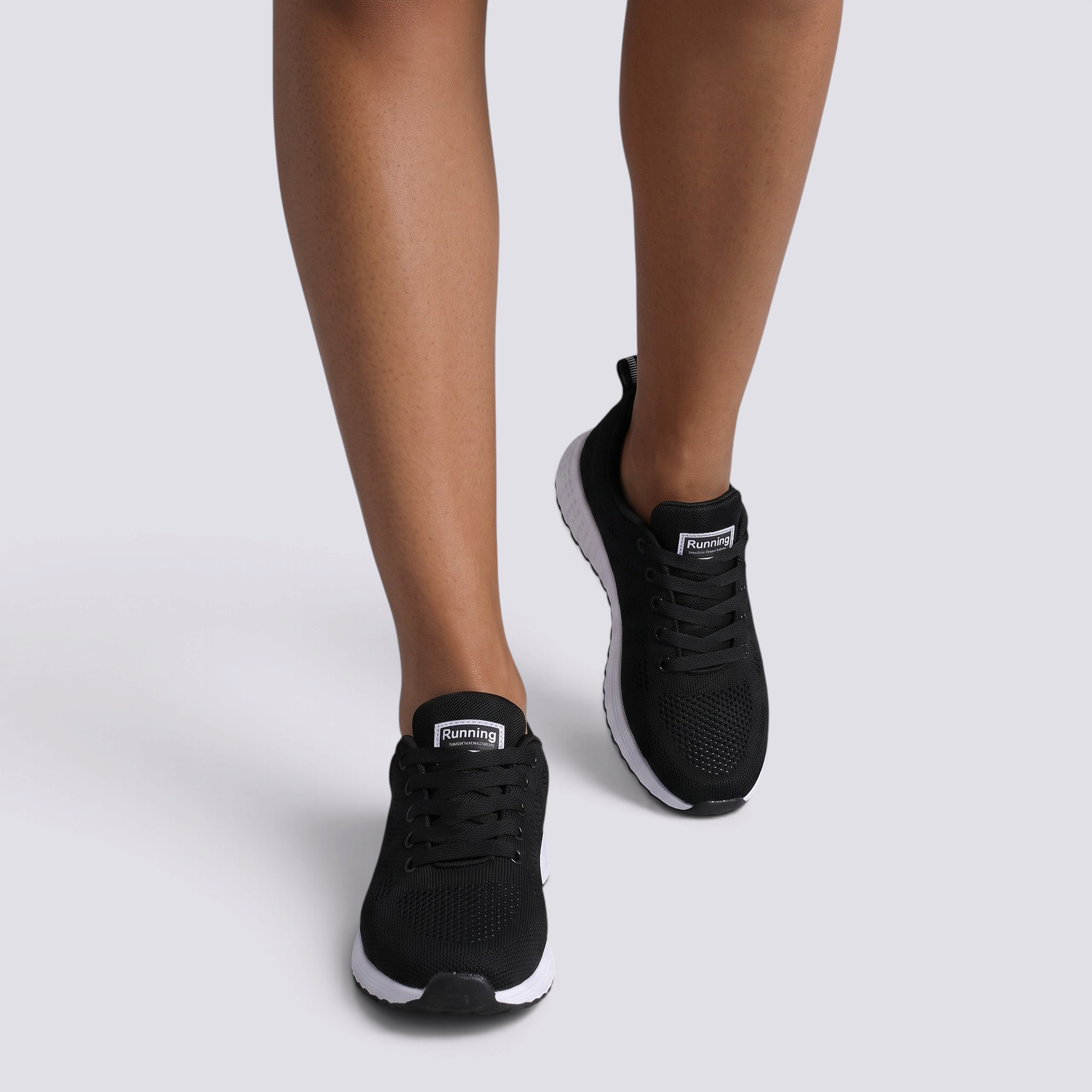 Essyro women's lightweight black breathable running sneakers with white soles worn on feet