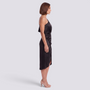 Essyro black one-shoulder midi party dress with asymmetrical hem and fluid fabric worn by a model in profile view