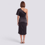 Back view of a woman wearing an Essyro black satin one-shoulder midi dress with an asymmetrical hem and heels.