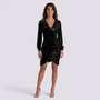 Essyro black velvet and sequin party dress with V-neck, long sleeves, and draped waist on a smiling model