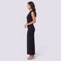 Essyro sleeveless black maxi dress with diagonal ruching and high round neck worn by a model in profile view