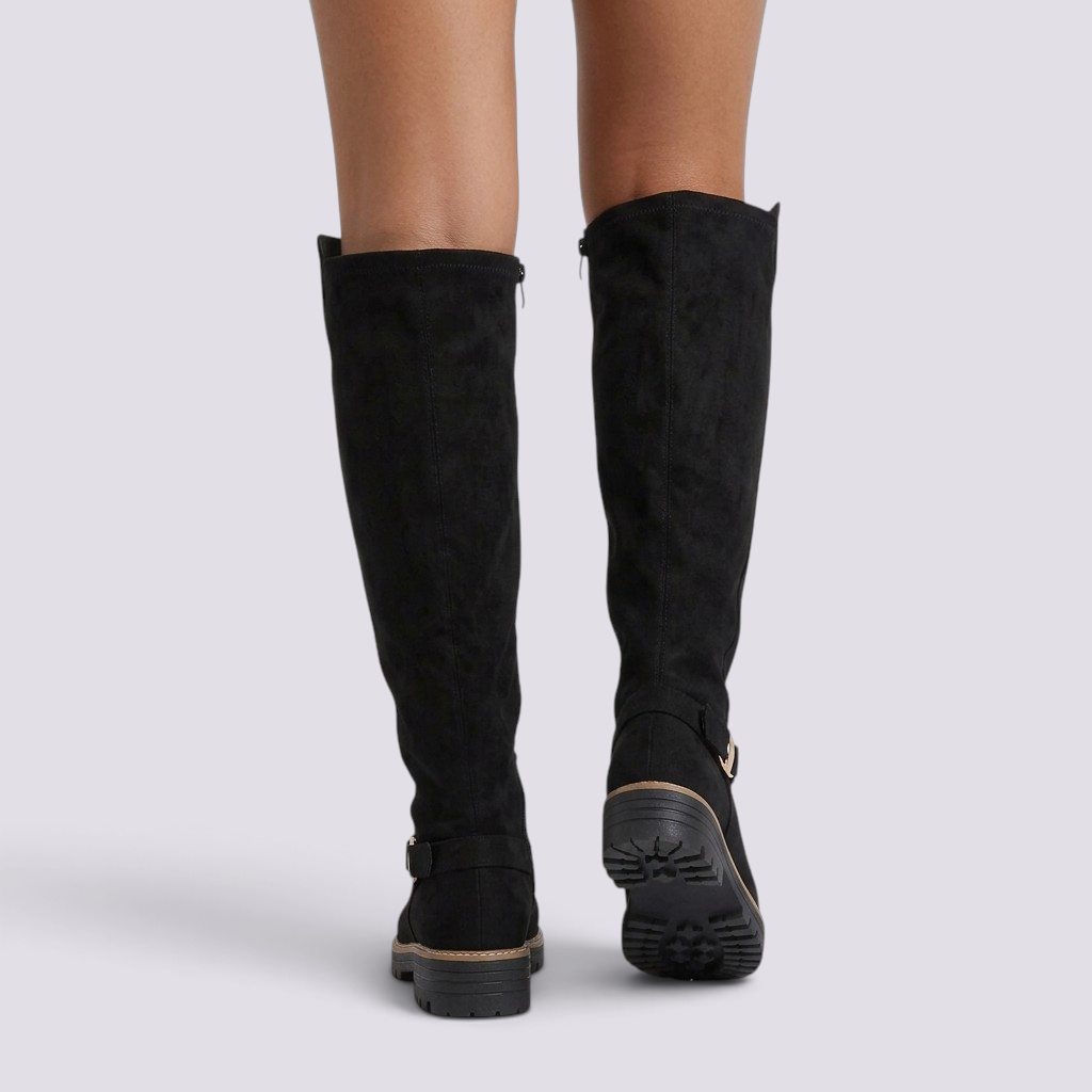 Essyro black suede knee-high boots with track soles and gold ankle buckle detail, viewed from the back