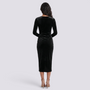 Essyro black velvet midi dress with long sleeves and draped waist detail, back view on a model with beige heels.