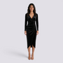 Essyro black velvet midi dress with long sleeves, V-neck, draped waist, and asymmetric hem worn by a smiling model.