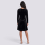 Back view of a woman wearing an Essyro black velvet short dress with long sleeves and a flared silhouette