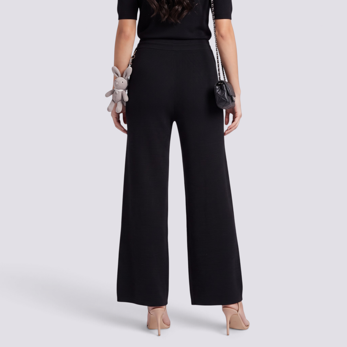 Essyro high-waisted black wide-leg knit trousers with a ribbed texture, worn by a woman from the back view.