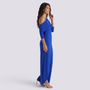 Essyro royal blue one-shoulder jumpsuit with draped long sleeve and wide-leg silhouette on a smiling model