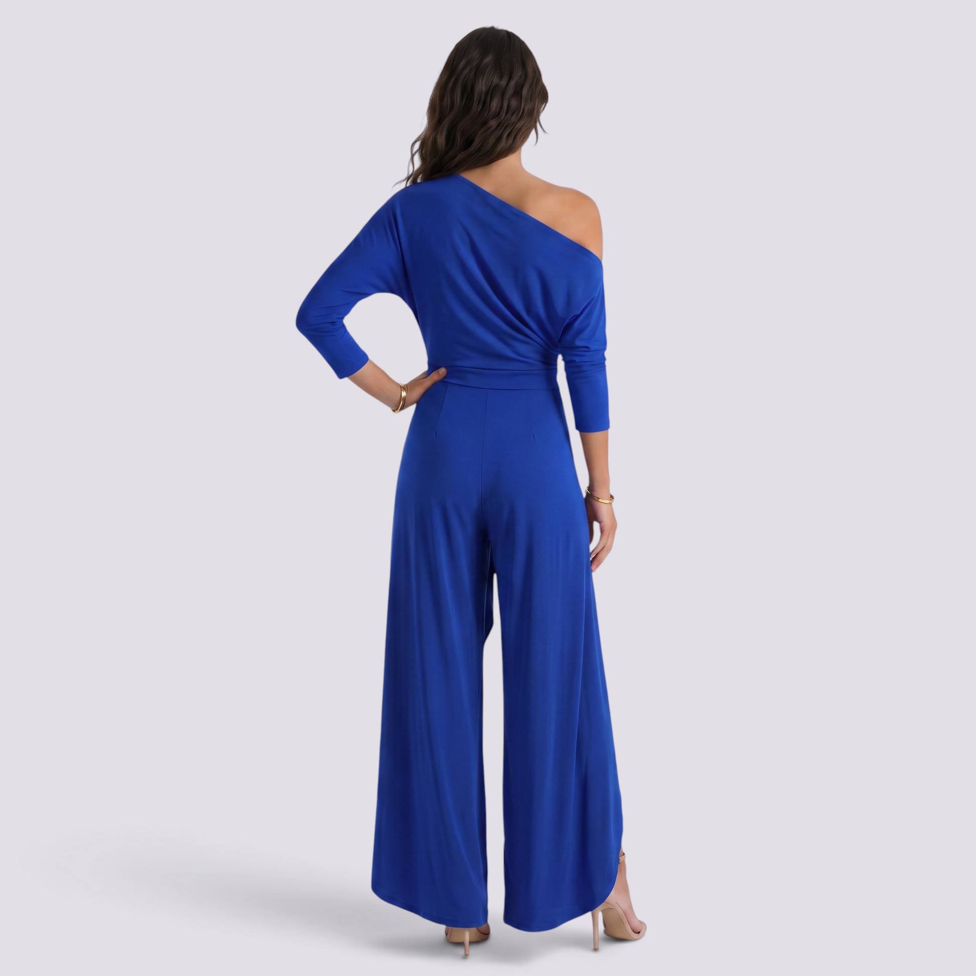 Essyro royal blue one-shoulder jumpsuit with long draped sleeve and wide-leg trousers worn by a woman from behind