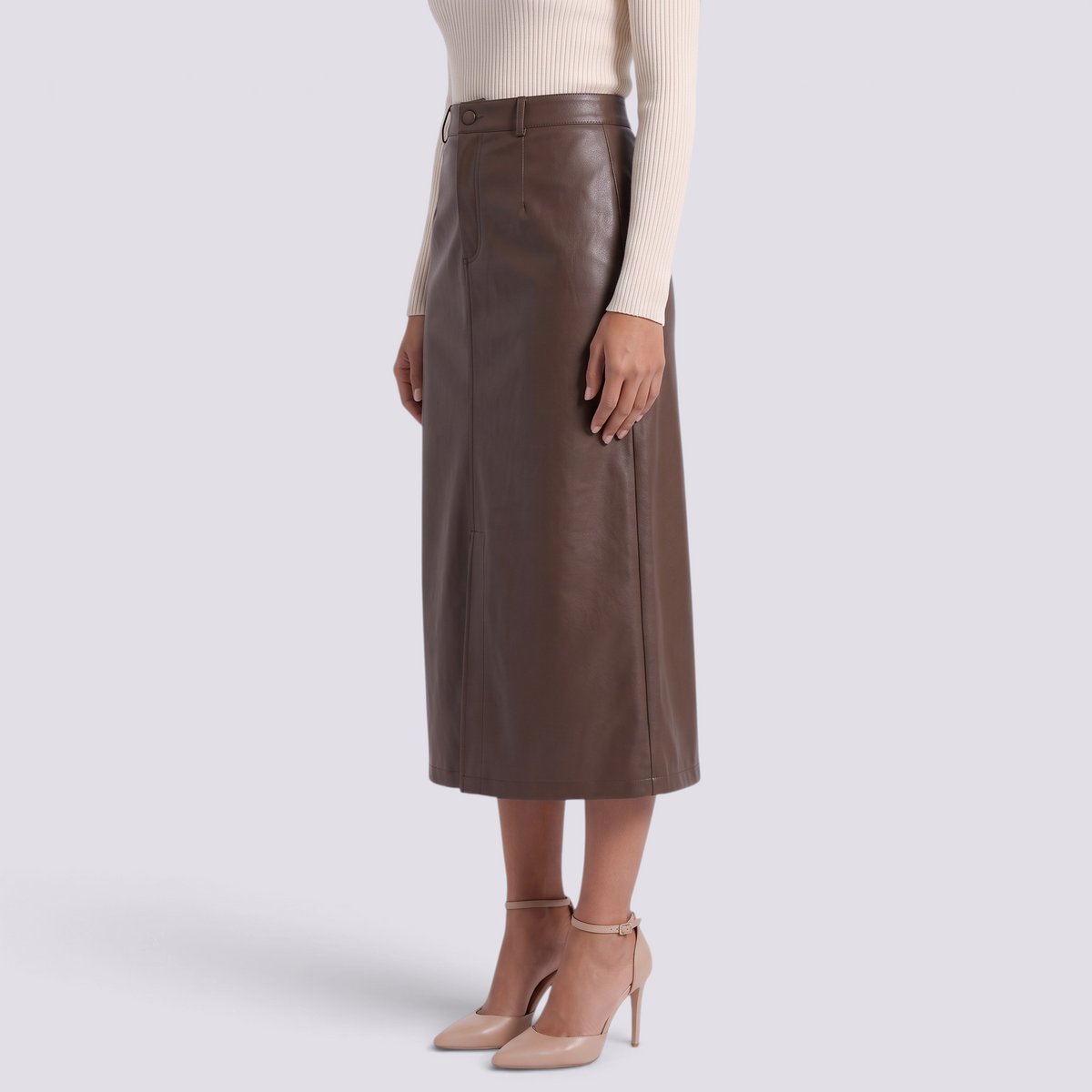 Essyro brown faux leather midi skirt with high waist, front slit, and side pockets worn with beige heels.