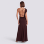 Essyro brown one-shoulder maxi dress with draped sleeve, open back, and crisscross straps on a model