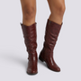 Essyro knee-high slouch boots in dark brown smooth finish with low block heel and decorative ankle strap