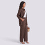 Essyro brown two-piece set with a loose long-sleeve shirt and wide-leg trousers worn by a woman with a straw bag.