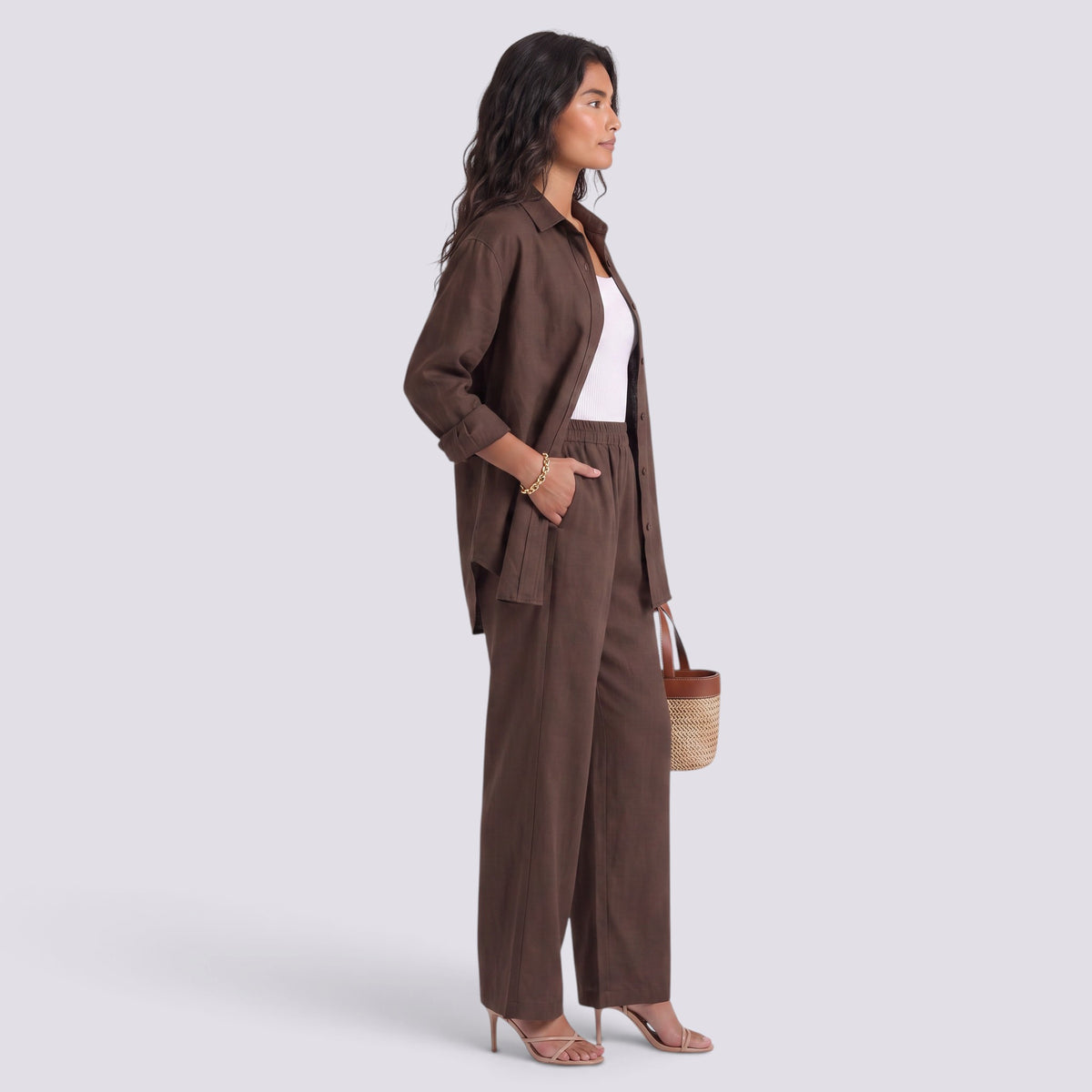 Essyro brown two-piece set with a loose long-sleeve shirt and wide-leg trousers worn by a woman with a straw bag.