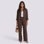 Essyro brown two-piece set with a loose long-sleeve shirt and wide-leg trousers worn by a woman with a woven bag.