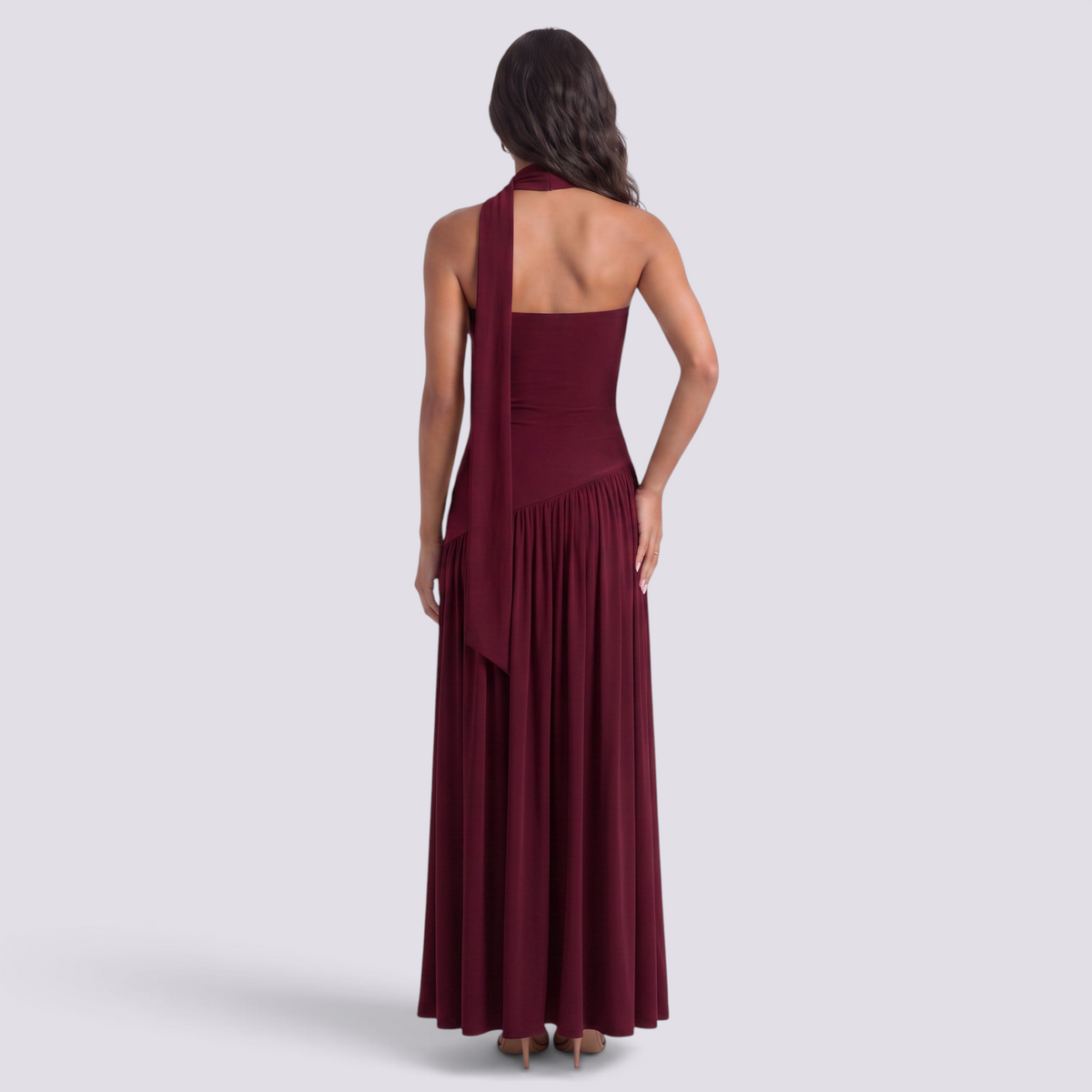 Essyro burgundy floor-length evening dress with halter neck and draped asymmetrical skirt, back view on a model.