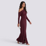 Essyro burgundy one-shoulder jumpsuit with draped long sleeve and wide-leg trousers worn by a model with a clutch.