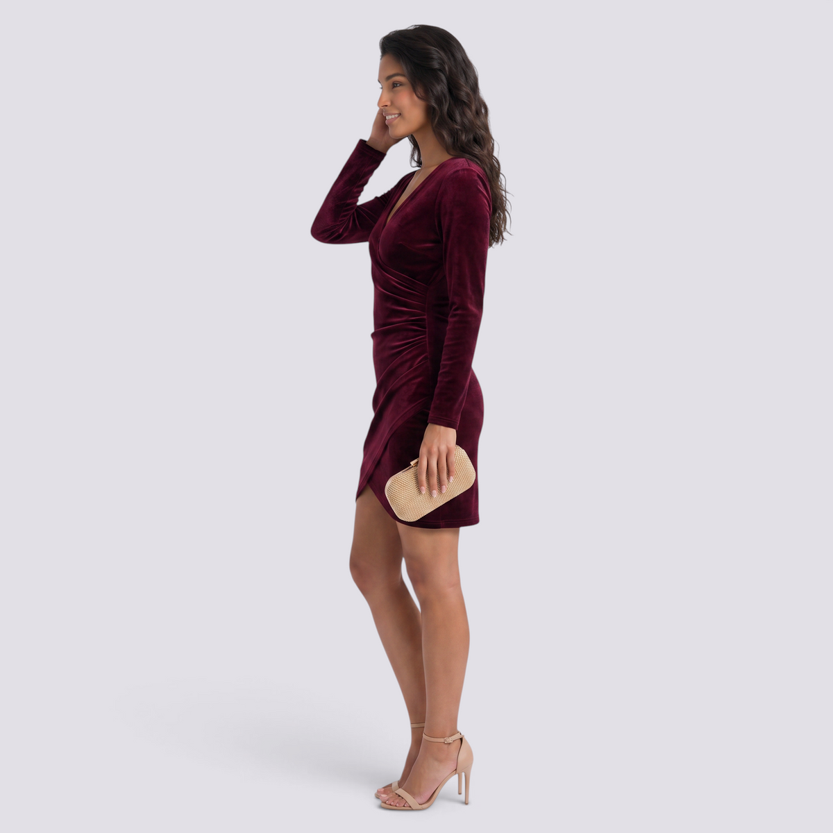 Essyro burgundy velvet party dress with V-neck, long sleeves, and asymmetric hem worn by a model in profile view.