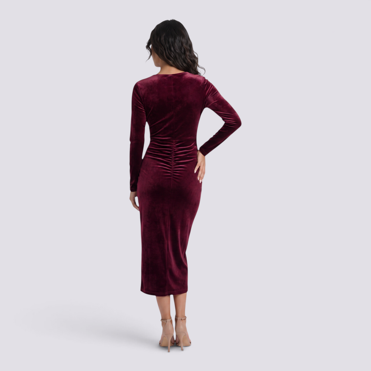 Back view of a woman wearing an Essyro burgundy velvet midi dress with long sleeves and a fitted silhouette.