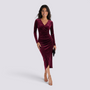 Essyro burgundy velvet midi dress with long sleeves, V-neck, draped waist, and asymmetric hem on a smiling model