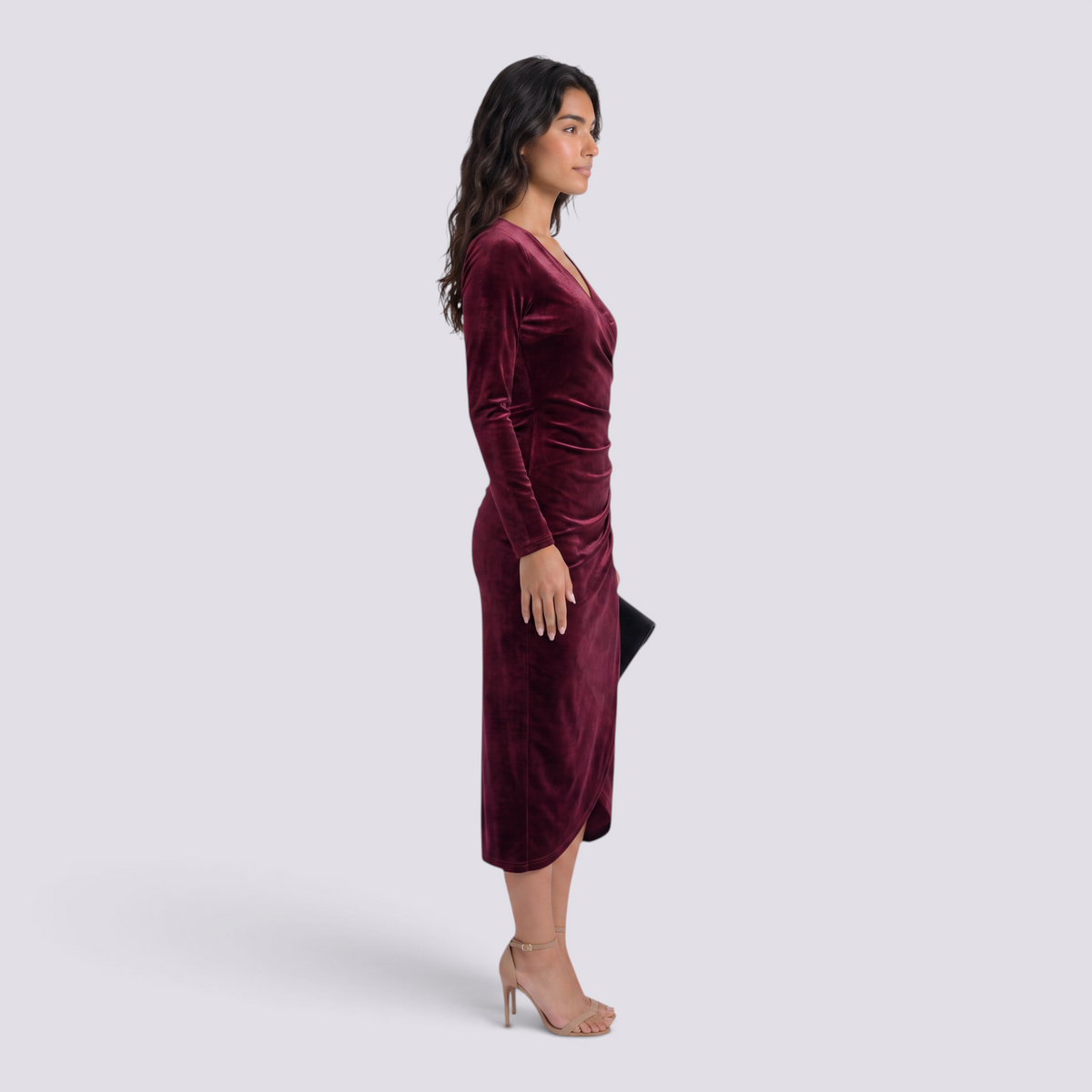 Essyro burgundy velvet midi dress with long sleeves, V-neck, and draped waist, worn by a model in profile view.