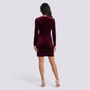Essyro burgundy velvet long-sleeve mini dress with an asymmetrical hem worn by a model from the back view