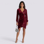 Essyro burgundy velvet and sequin party dress with V-neck, long sleeves, and draped waist on a smiling model