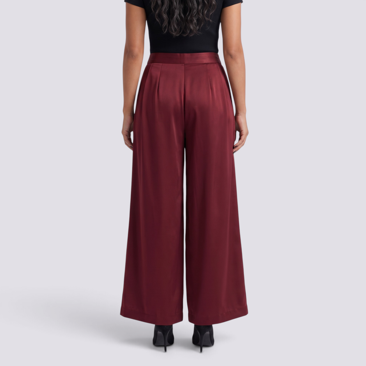 Essyro elegant wide-leg trousers in deep burgundy satin fabric, back view on a model with black top and heels.